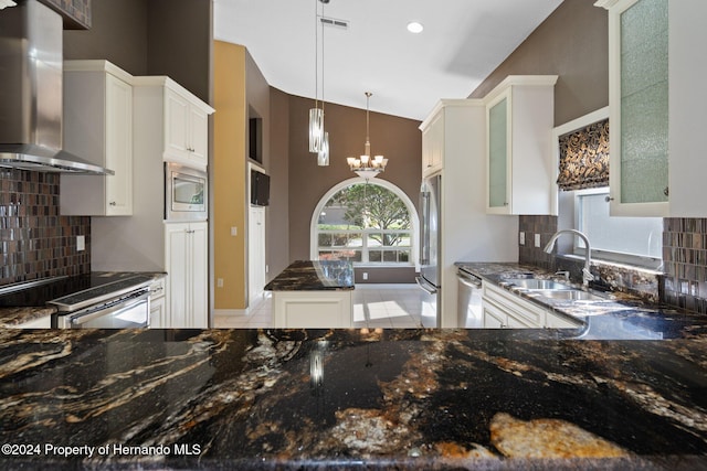 kitchen with white cabinetry, wall chimney exhaust hood, hanging light fixtures, stainless steel appliances, and backsplash