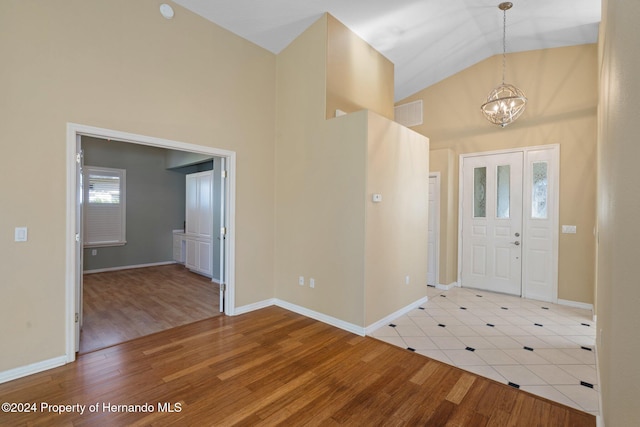 entryway with light wood-type flooring, high vaulted ceiling, and an inviting chandelier