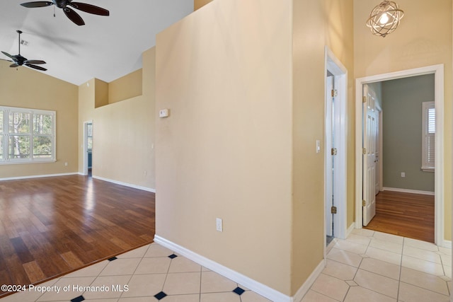 hallway with light tile patterned floors and high vaulted ceiling