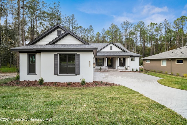 19504 Sheltered Hill Dr, Brooksville, FL 34601 - view of front of home featuring a porch, decorative driveway, a shingled roof, stucco siding, and a front lawn