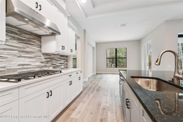 kitchen with white cabinets, sink, dark stone countertops, light wood-type flooring, and appliances with stainless steel finishes