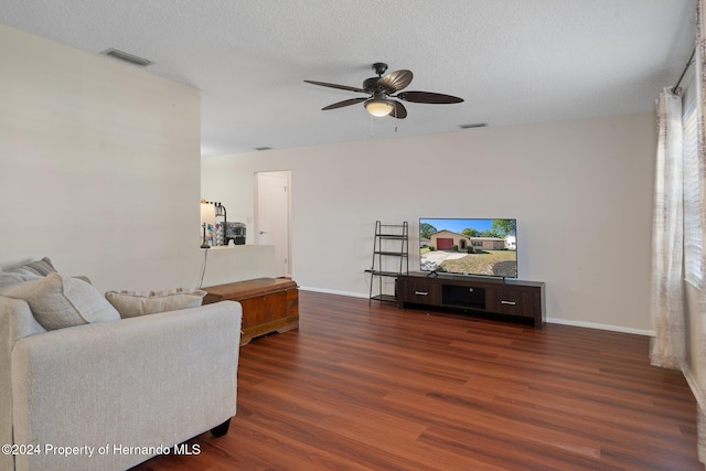 living room with a textured ceiling, dark hardwood / wood-style flooring, and ceiling fan