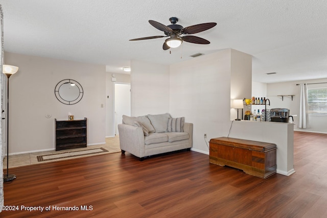 unfurnished living room featuring ceiling fan, dark hardwood / wood-style flooring, and a textured ceiling