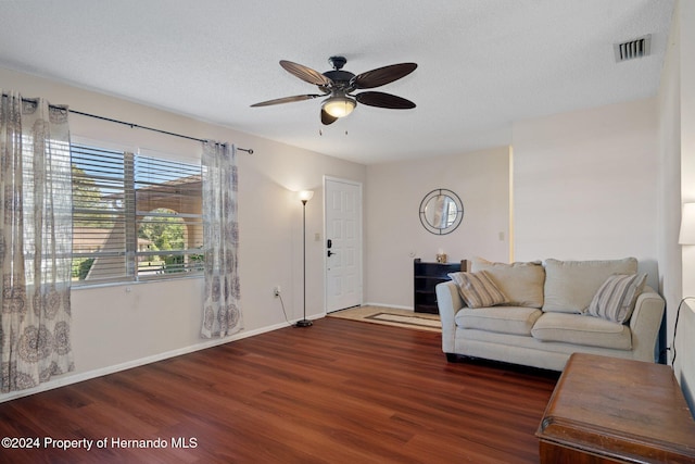 living room with a textured ceiling, ceiling fan, and dark hardwood / wood-style floors