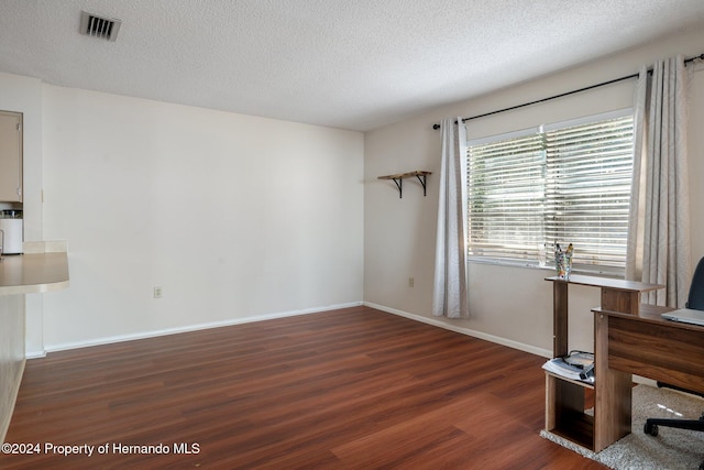 unfurnished office with dark hardwood / wood-style flooring and a textured ceiling