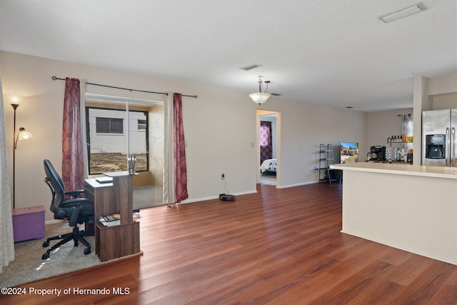 interior space with stainless steel fridge with ice dispenser, dark hardwood / wood-style flooring, a textured ceiling, and hanging light fixtures