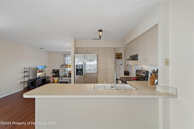 kitchen with sink, dark hardwood / wood-style floors, a textured ceiling, appliances with stainless steel finishes, and kitchen peninsula