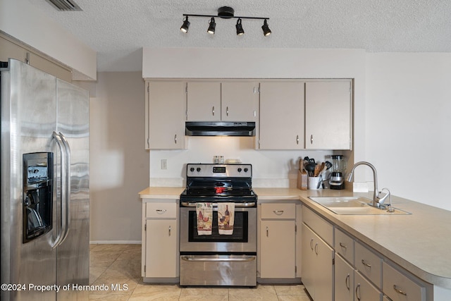 kitchen featuring sink, a textured ceiling, light tile patterned flooring, kitchen peninsula, and stainless steel appliances