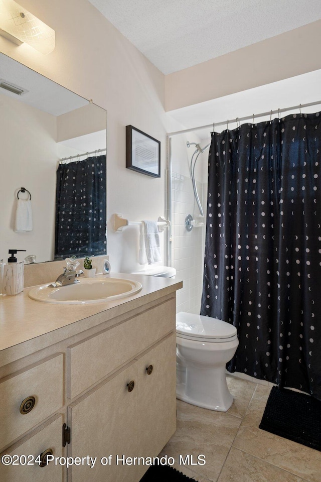 bathroom with vanity, a shower with curtain, tile patterned flooring, toilet, and a textured ceiling