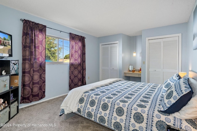 carpeted bedroom featuring a textured ceiling and two closets