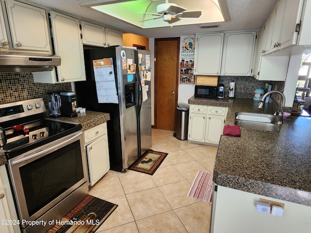 kitchen featuring sink, light tile patterned floors, range hood, appliances with stainless steel finishes, and white cabinetry