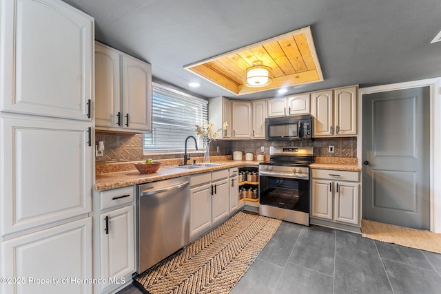 kitchen featuring a raised ceiling, sink, backsplash, dark tile patterned flooring, and stainless steel appliances