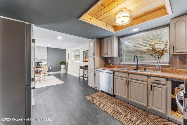 kitchen with stainless steel appliances, a raised ceiling, sink, and backsplash