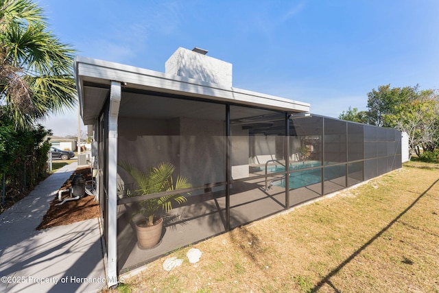 rear view of house featuring a fenced in pool, a yard, a patio area, and glass enclosure