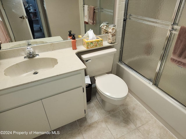 full bathroom featuring toilet, tile patterned flooring, vanity, and combined bath / shower with glass door