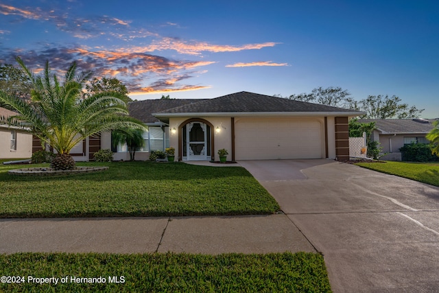 ranch-style house featuring a lawn and a garage