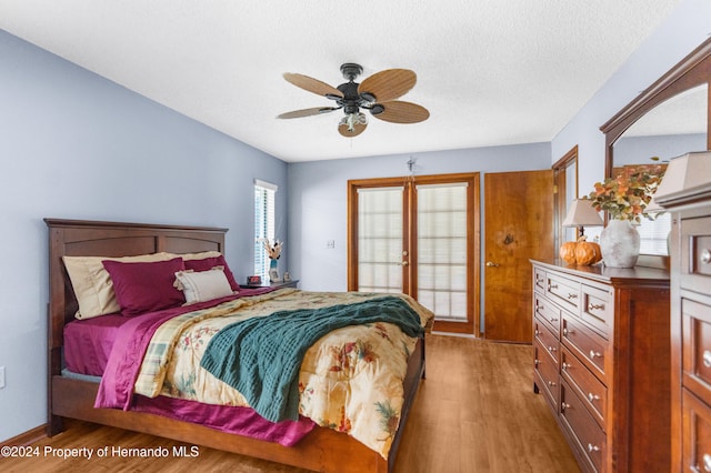 bedroom featuring ceiling fan, a textured ceiling, and light wood-type flooring