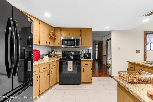 kitchen with light stone countertops, light hardwood / wood-style flooring, and black appliances