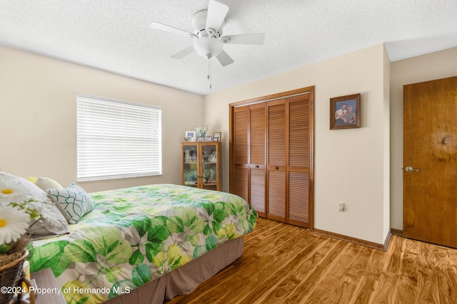 bedroom with a textured ceiling, a closet, hardwood / wood-style flooring, and ceiling fan