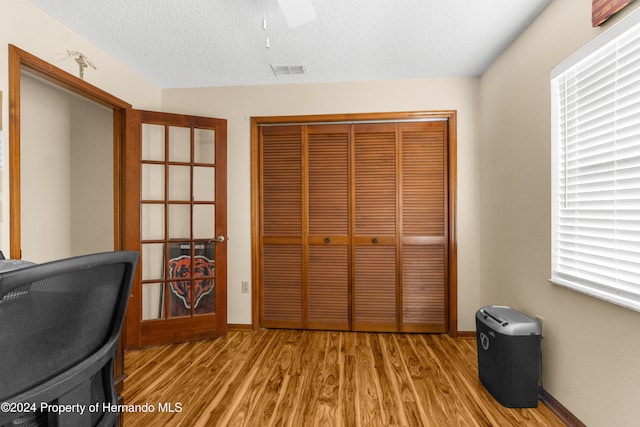 home office featuring ceiling fan, light hardwood / wood-style flooring, and a textured ceiling