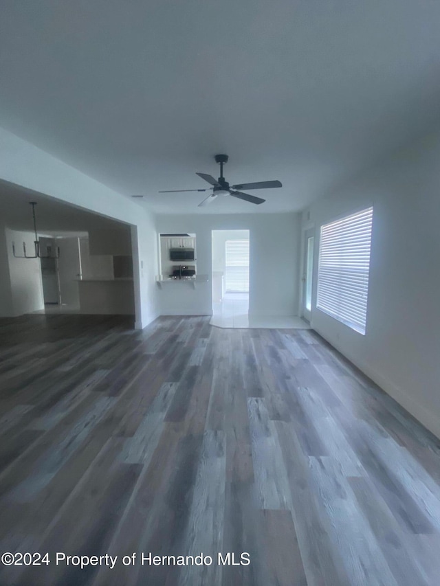 unfurnished living room with dark wood-type flooring and ceiling fan