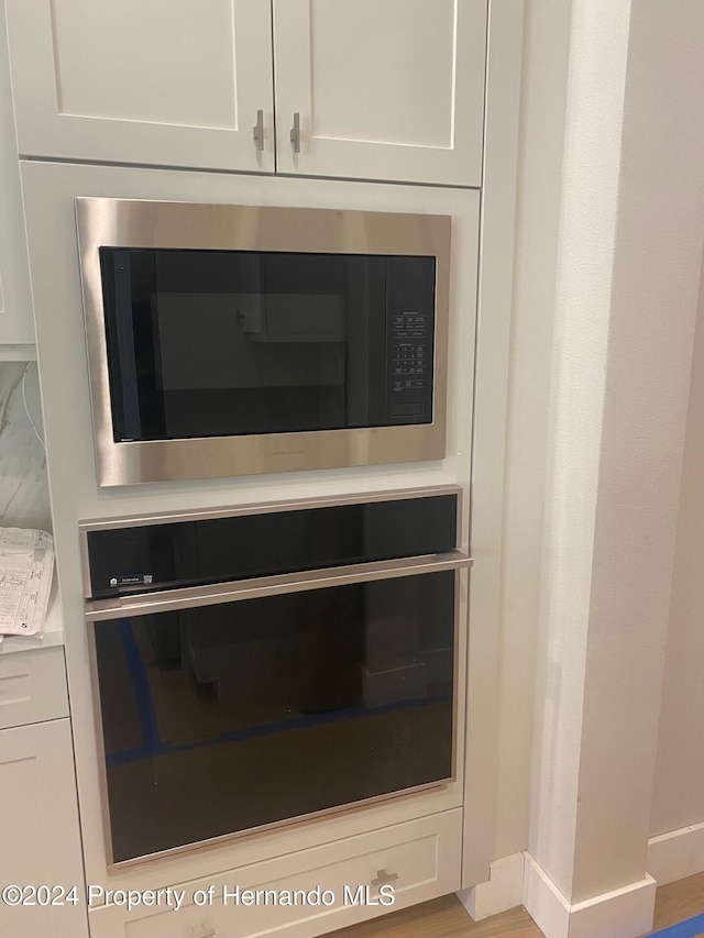 4817 Majestic Hills Loop, Brooksville, FL 34601 - kitchen view of stainless steel microwave, black oven, light countertops, and white cabinets