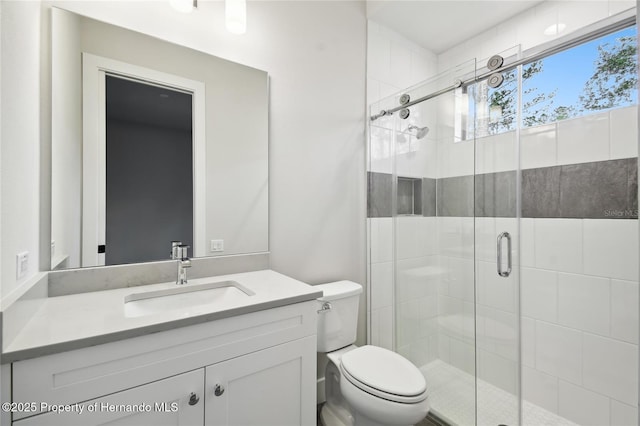 bathroom with vanity, a shower with shower door, and toilet