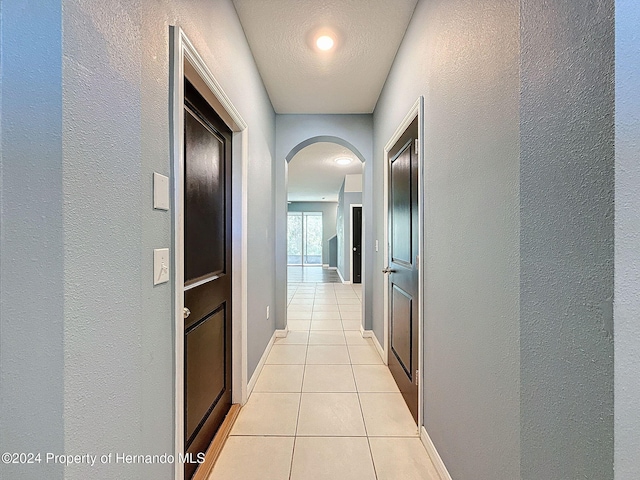 hall with light tile patterned floors and a textured ceiling