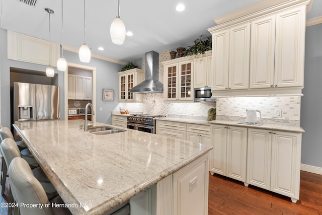 kitchen with pendant lighting, wall chimney range hood, dark hardwood / wood-style floors, appliances with stainless steel finishes, and a kitchen bar