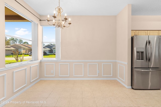 unfurnished dining area with light tile patterned floors and an inviting chandelier