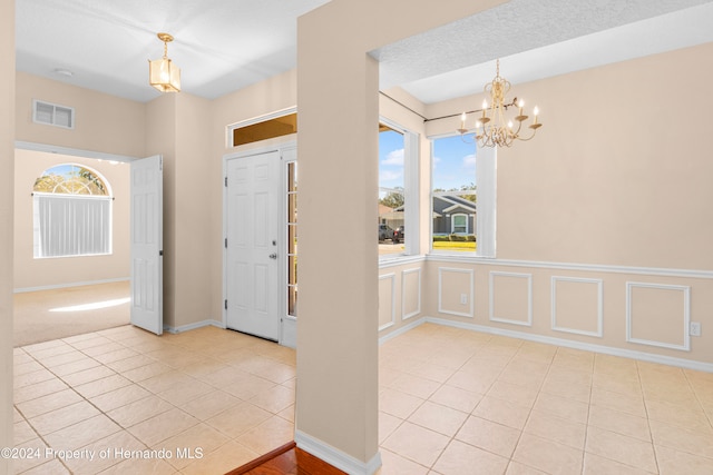 foyer featuring light tile patterned floors, a chandelier, and a textured ceiling