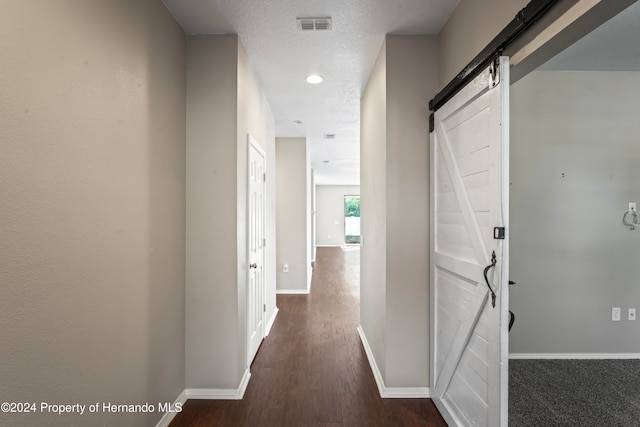 hallway with dark hardwood / wood-style flooring, a barn door, and a textured ceiling