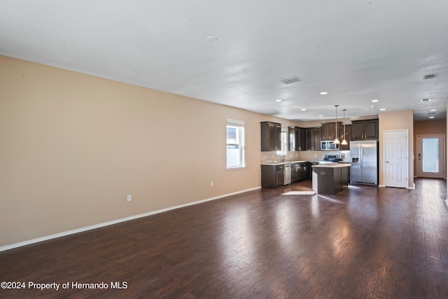 kitchen featuring appliances with stainless steel finishes, dark brown cabinets, a center island, dark hardwood / wood-style floors, and hanging light fixtures