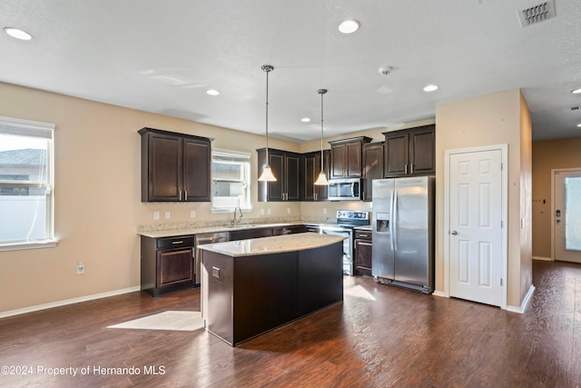 kitchen with pendant lighting, stainless steel appliances, a kitchen island, and a healthy amount of sunlight