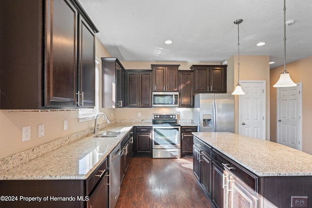 kitchen featuring dark hardwood / wood-style flooring, stainless steel appliances, sink, pendant lighting, and a kitchen island