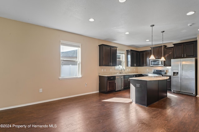 kitchen with appliances with stainless steel finishes, sink, a center island, dark hardwood / wood-style floors, and hanging light fixtures