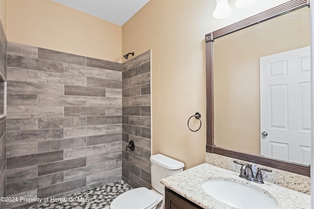 bathroom featuring tiled shower, vanity, and toilet