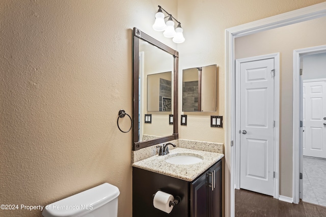 bathroom with hardwood / wood-style flooring, vanity, and toilet