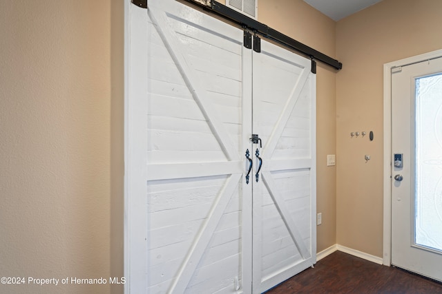 entrance foyer with dark hardwood / wood-style flooring, a barn door, and a healthy amount of sunlight