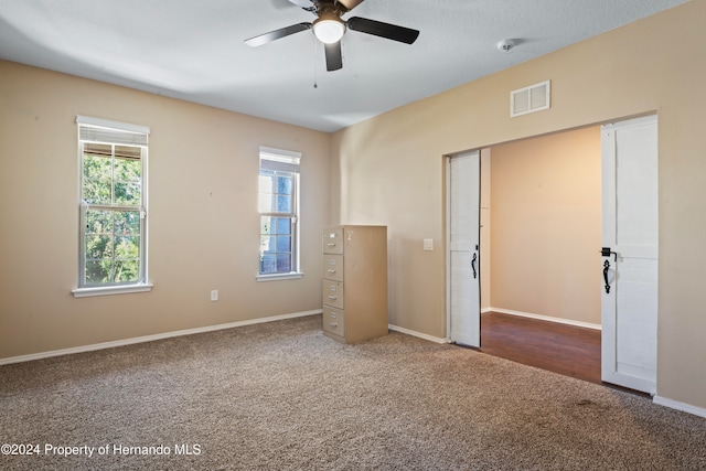 unfurnished bedroom with carpet flooring, multiple windows, and ceiling fan