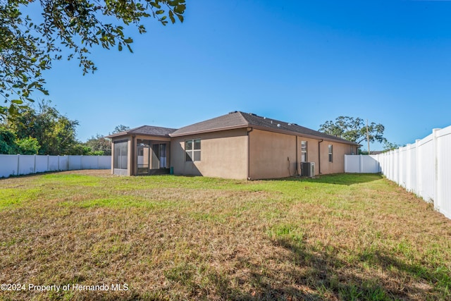 rear view of property with a sunroom, a yard, and central air condition unit