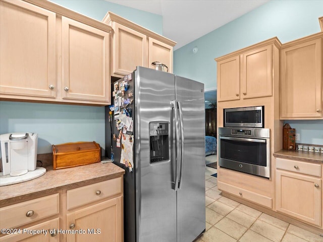 kitchen with light brown cabinetry, stainless steel appliances, and light tile patterned flooring