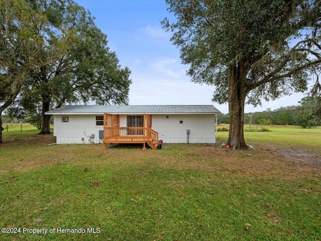 back of property with a lawn and a wooden deck