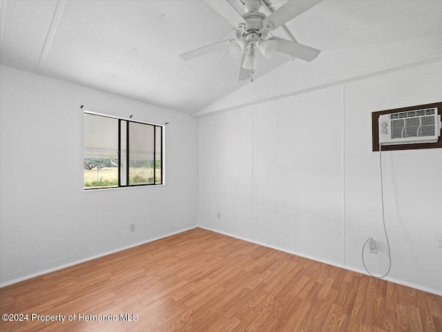 spare room featuring ceiling fan, a wall mounted AC, hardwood / wood-style floors, a textured ceiling, and vaulted ceiling