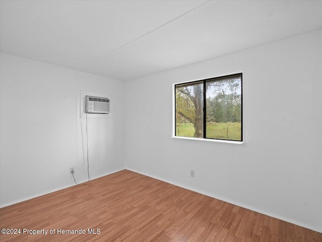 spare room with a wall unit AC and hardwood / wood-style flooring