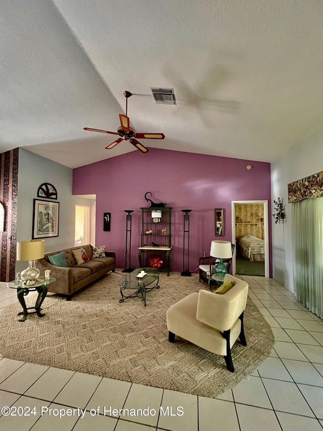 living room with a textured ceiling, ceiling fan, tile patterned flooring, and vaulted ceiling