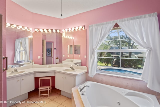 bathroom with tile patterned flooring, vanity, and tiled bath