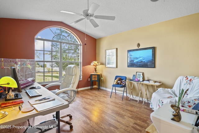 home office featuring ceiling fan, a healthy amount of sunlight, wood-type flooring, and lofted ceiling