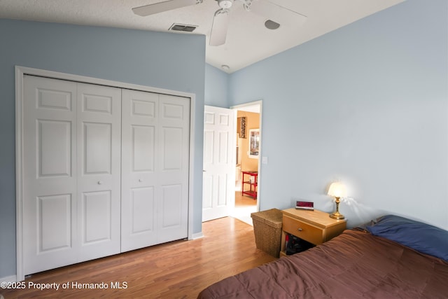 bedroom with ceiling fan, lofted ceiling, wood-type flooring, and a closet