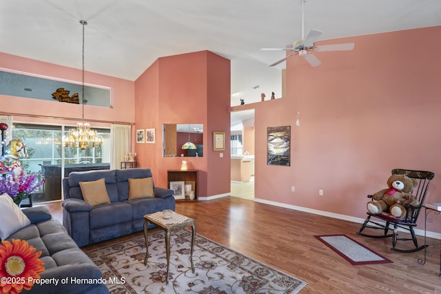 living room with hardwood / wood-style floors, high vaulted ceiling, and ceiling fan with notable chandelier